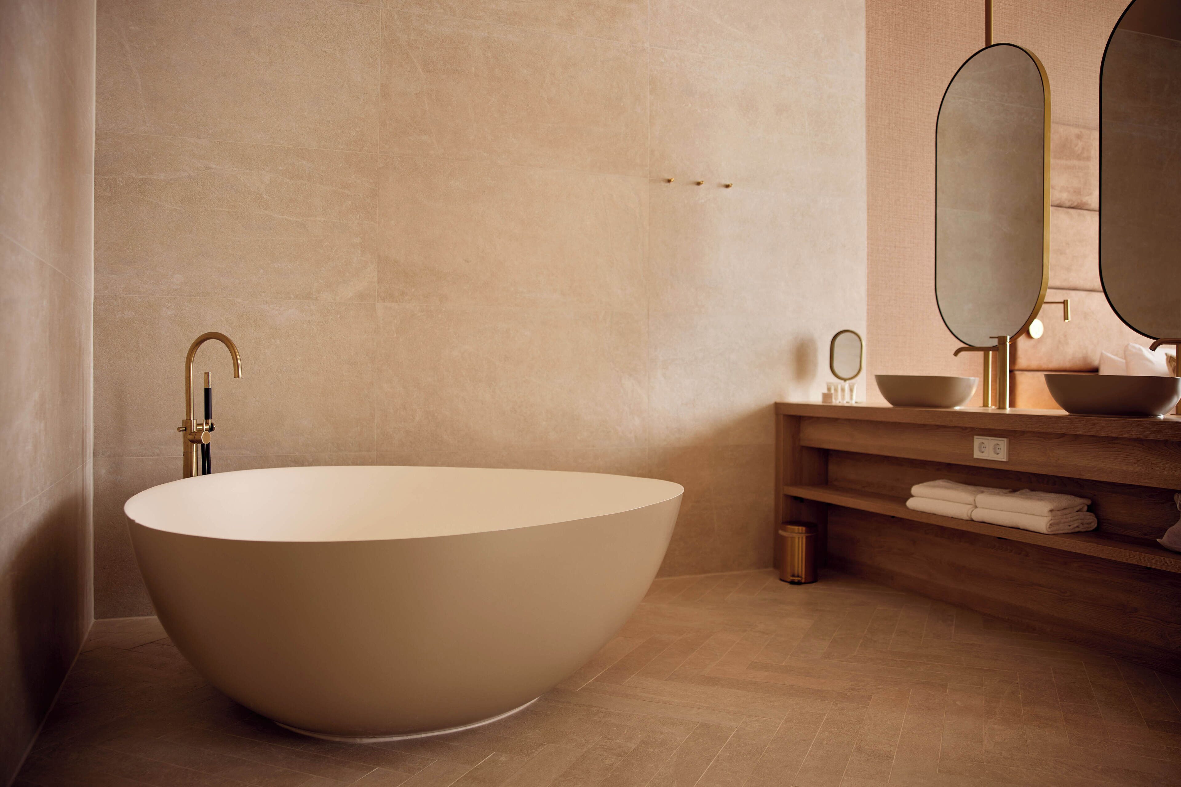 A modern bathroom with a freestanding bathtub, a wooden vanity with a mirror, and a towel rack.