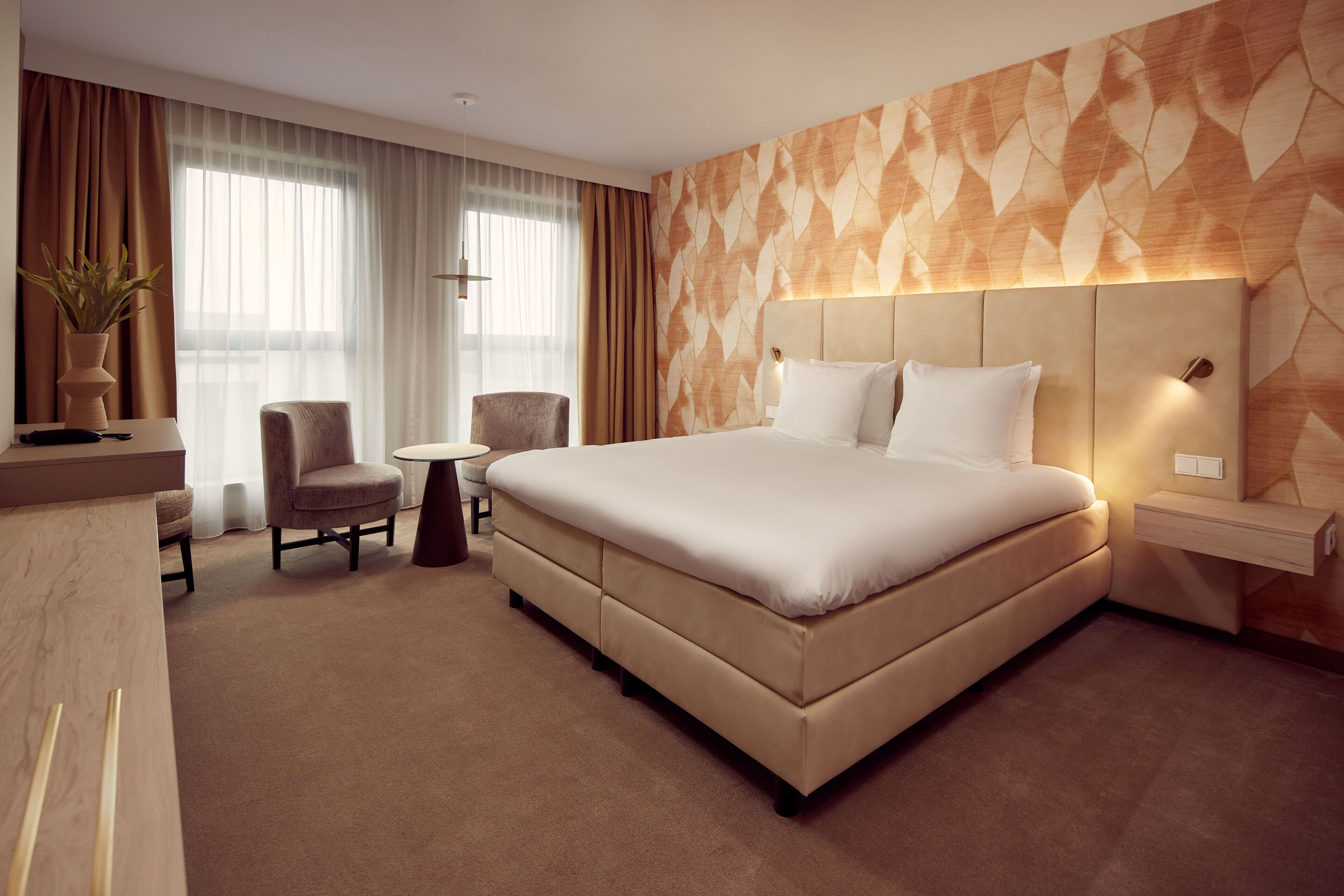 Een moderne hotelkamer met een groot bed, een bureau, een stoel en een klein tafeltje.