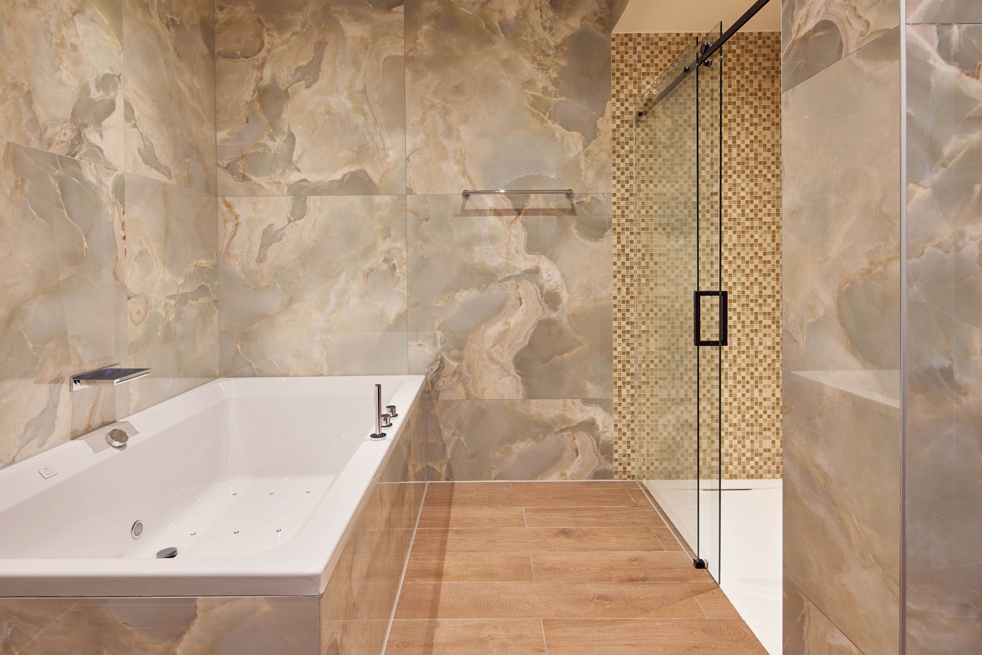 A modern bathroom with a freestanding bathtub, a glass shower enclosure, and a marble wall.