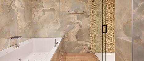 A modern bathroom with a freestanding bathtub, a glass shower enclosure, and a marble wall.