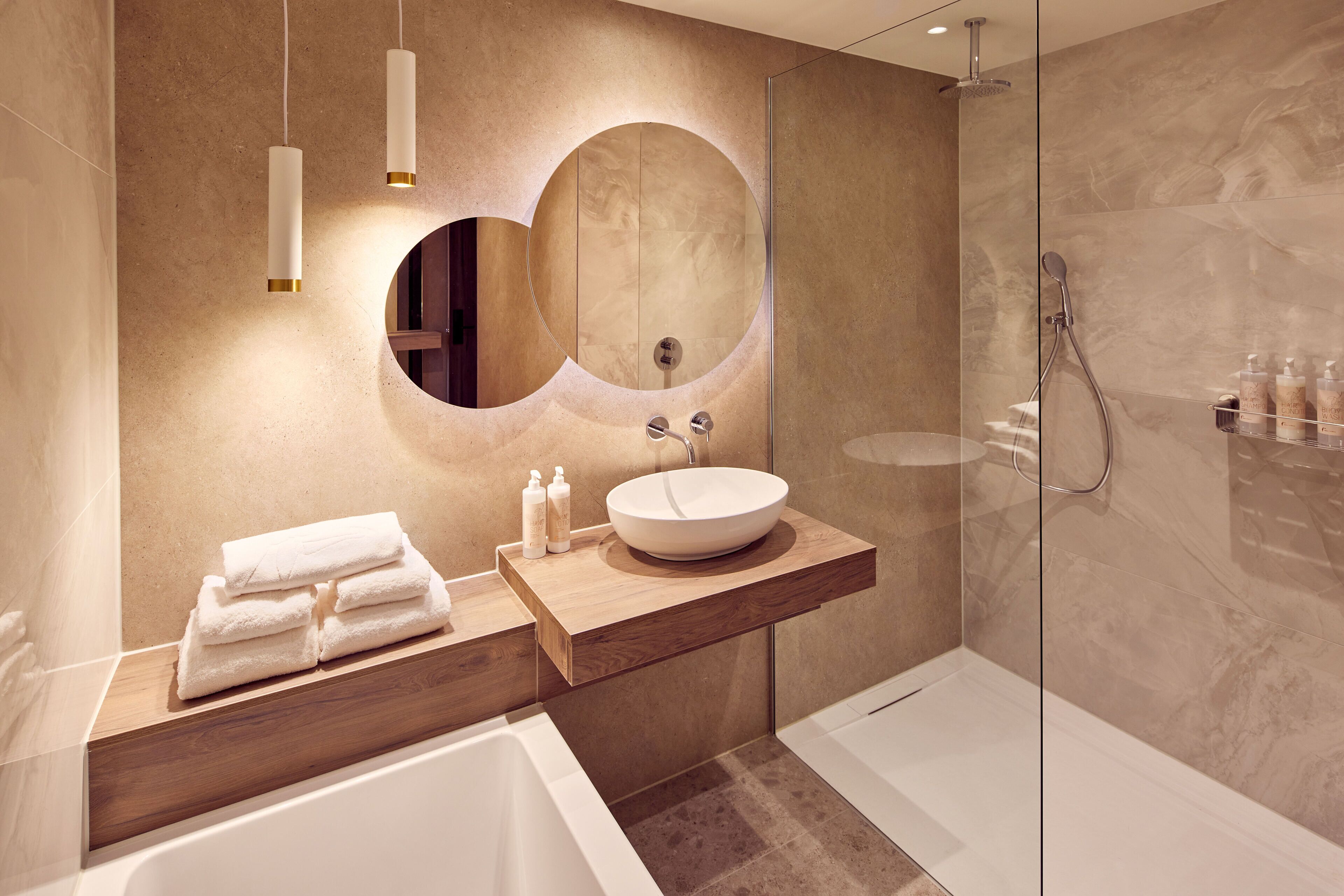 Un bagno moderno con una grande vasca, uno specchio rotondo e un mobile vanitario in legno.