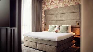A modern bedroom with a large bed, a headboard with a built-in TV, and a floral wallpaper.