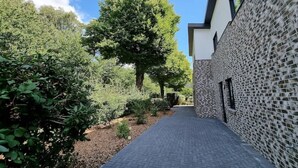 A narrow pathway leading to a modern building with a stone facade and large windows. - "achterwasser" - Moderne Ferienwohnung in Varel (Varel)