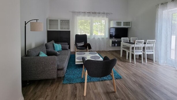 A modern living room with a sofa, a coffee table, and a dining area with chairs. - "achterwasser" - Moderne Ferienwohnung in Varel (Varel)