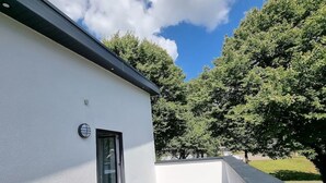 A modern building with a white exterior, a wooden deck, and a glass door. - "achterwasser" - Moderne Ferienwohnung in Varel (Varel)