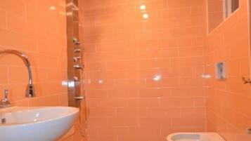 A bathroom with orange tiled walls, a white sink, and a toilet.