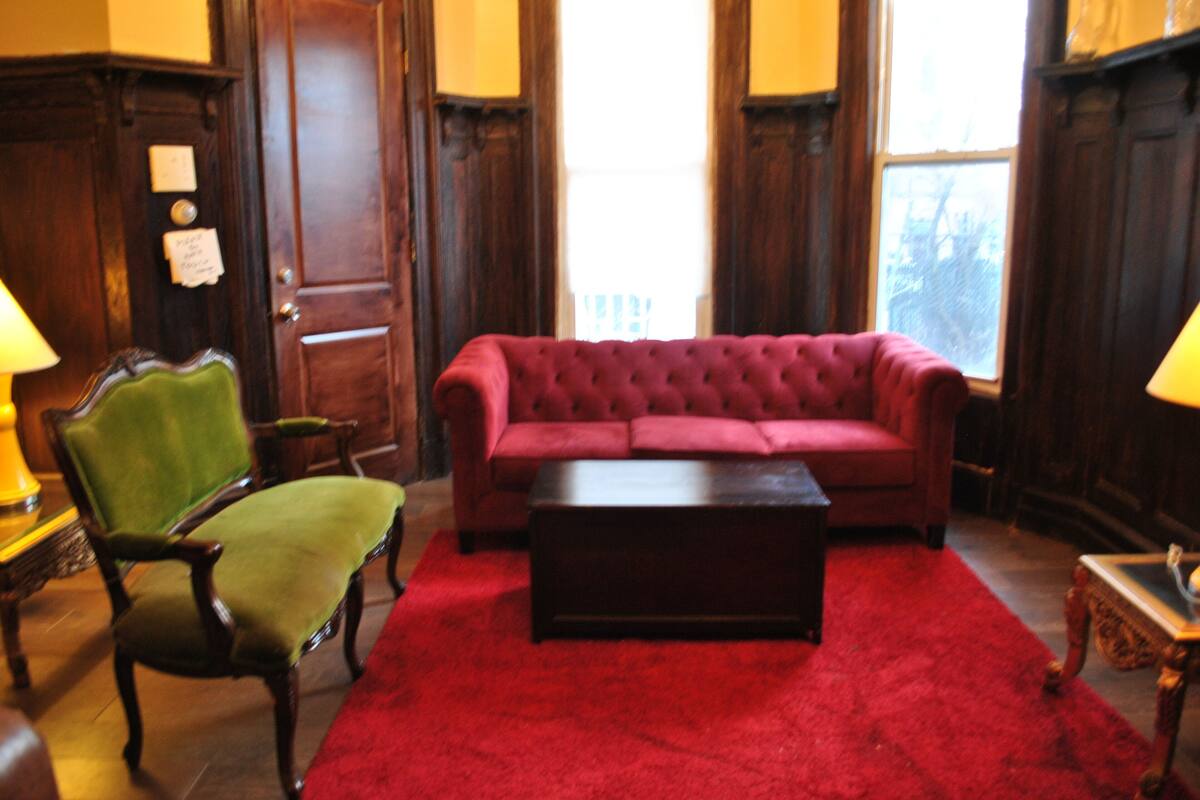 A room with a red sofa, a green armchair, and a wooden coffee table.