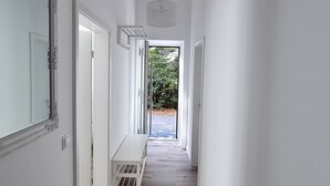 A hallway with a wooden floor, white walls, and a large mirror on the left. - "steuerbord" - Moderne Ferienwohnung in Varel (Varel)