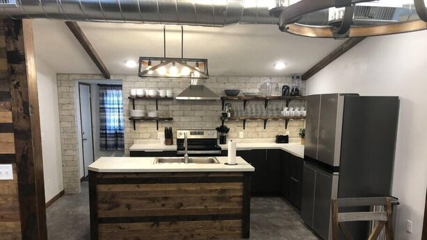 A modern kitchen with a central island, stainless steel appliances, and a hanging light fixture.