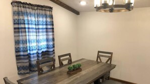 A dining area with a wooden table, four chairs, a bench, and a chandelier.