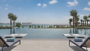 Zona de piscina con sillones de descanso y vistas al mar y al horizonte de la ciudad.