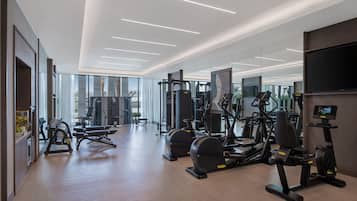 Un gimnasio moderno con diverso equipo de ejercicio, amplias ventanas y una televisión de pantalla plana.