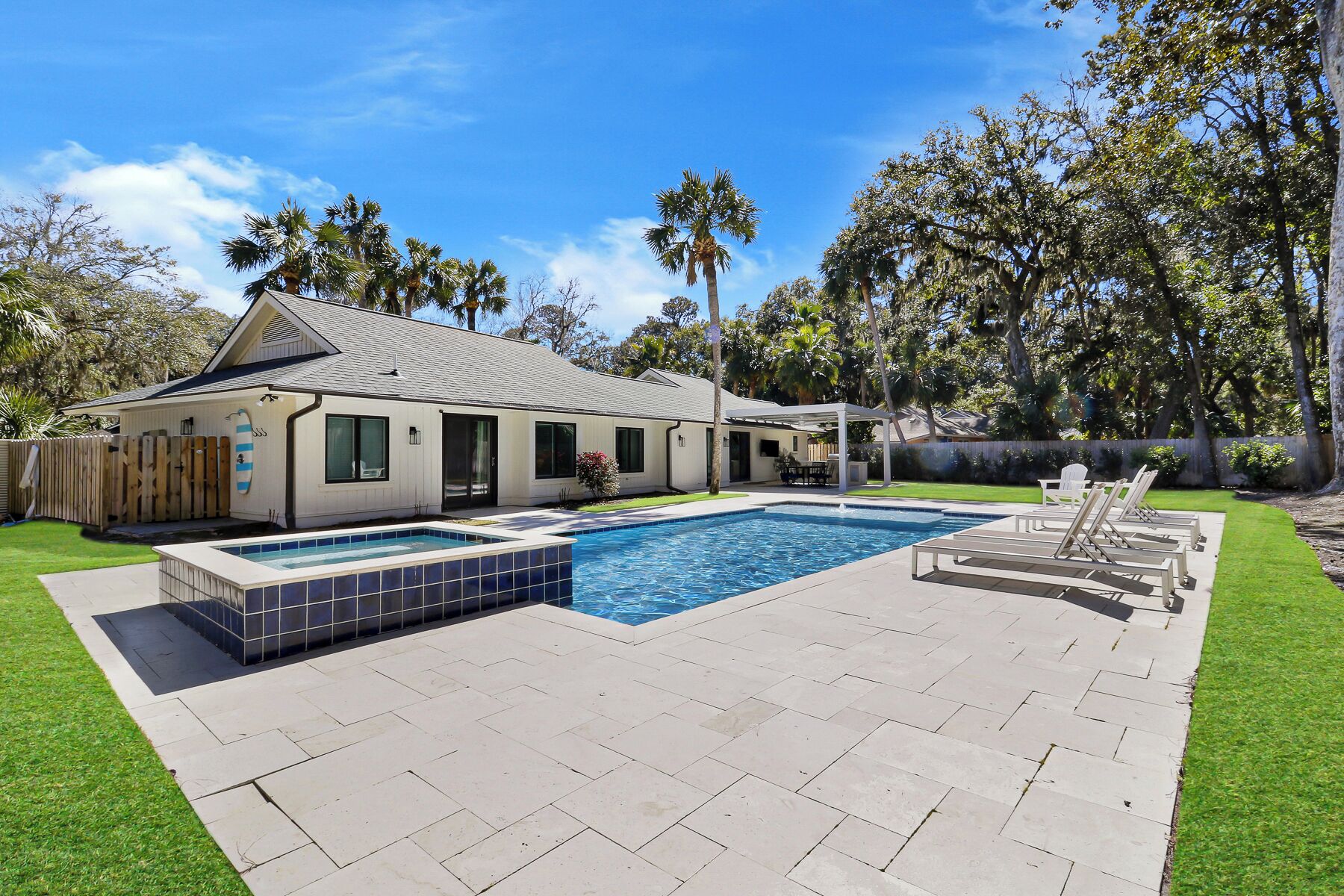 Ein Haus mit Swimmingpool, überdachter Terrasse und umzäunter Garten.