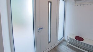 A room with a sliding door, a bench, and a radiator. - "backbord"- Moderne Ferienwohnung in Varel (Varel)