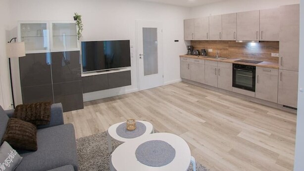 A modern apartment with a living room, kitchen, and a TV mounted on the wall. - "backbord"- Moderne Ferienwohnung in Varel (Varel)