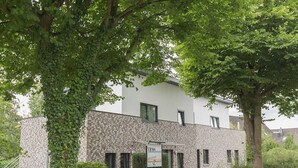 A building with a stone facade, multiple windows, and a sign indicating a business or service. - "backbord"- Moderne Ferienwohnung in Varel (Varel)