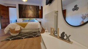 A bedroom with a bed, a large painting, a TV, a mirror, and a 'Relax' sign.