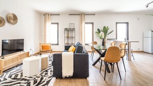 Uma sala de estar moderna com sofá, televisão e área de jantar.