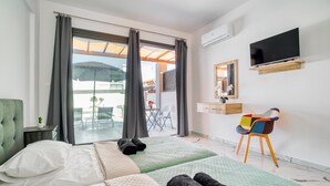 Una camera d'albergo con due letti, una TV, una scrivania con una sedia e un balcone con sedute all'aperto.