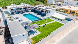 Un hotel moderno con piscina sul tetto, area salotto all'aperto e prato curato.
