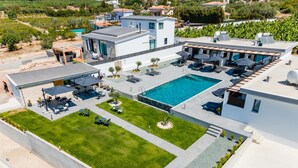 A modern hotel with a rooftop pool, outdoor seating, and a well-maintained lawn.