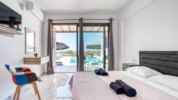 A hotel room with a bed, a chair, a desk, and a view of a swimming pool.