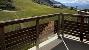 A balcony with a view of a green hillside and a distant mountain range.