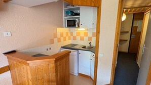 A compact kitchen with wooden cabinetry, a microwave, and a sink.