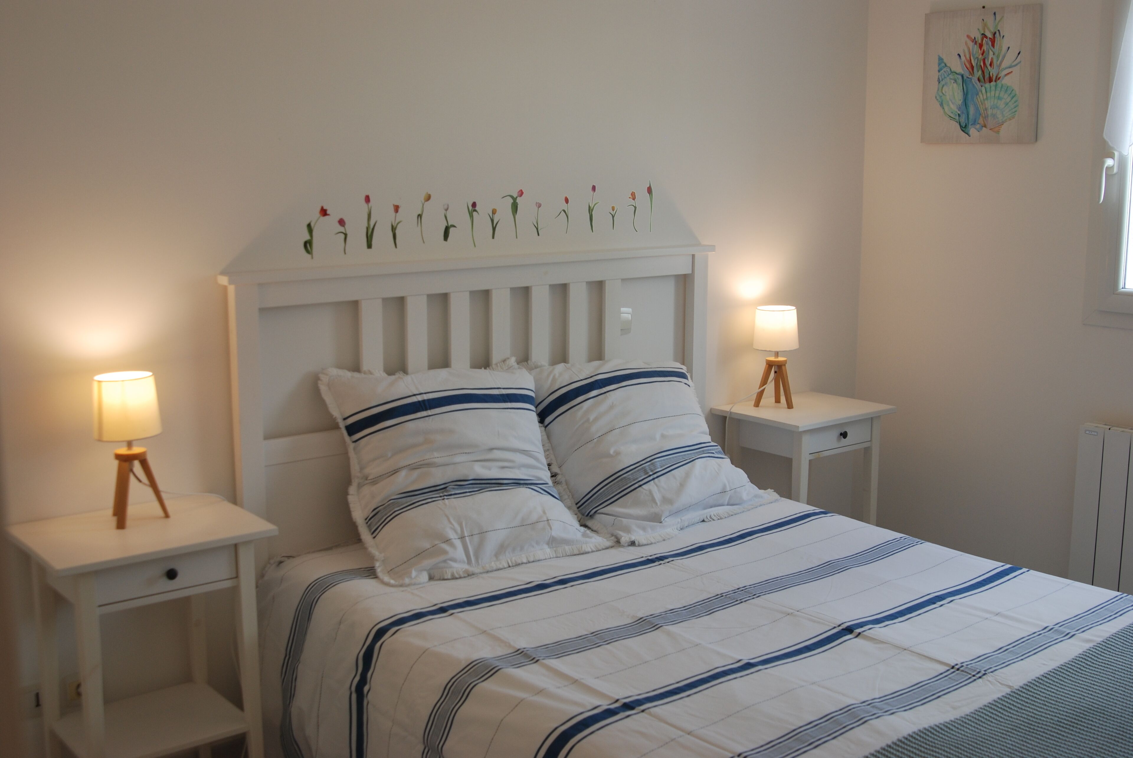 Une chambre à coucher avec un lit, deux tables de chevet et un élément décoratif mural.