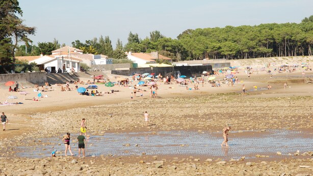 A beach with people, umbrellas, and buildings in the background. - Maison Individuelle Avec Jardin (Angles)