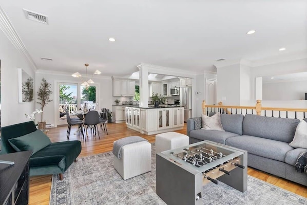 A spacious living area with a sofa, ottoman, and a foosball table. - New Beach Home near Stamford Downtown/Shippan (Stamford)