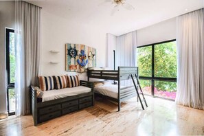 Ein Schlafzimmer mit einem Etagenbett, einer Schlafcouch, einer Leiter und einem großen Fenster mit Blick ins Grüne.