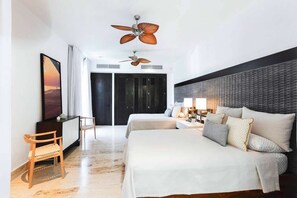 Une chambre d’hôtel avec deux lits, un bureau, une chaise, un ventilateur de plafond et une vue sur l’extérieur.