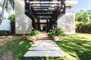 Un chemin menant à un bâtiment à l’architecture moderne, doté d’une allée couverte et d’une série de marches.