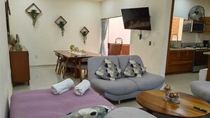 A living room with a sofa, a coffee table, and a dining area with a table and chairs.