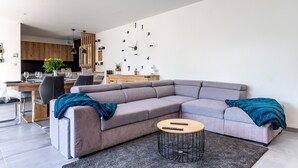 En moderne stue med en modulsofa, et rundt sofabord og et spiseområde med et træbord og stole.