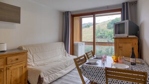 A cozy room with a sofa, a dining table with chairs, a television, and a view of the outdoors. - Soyouz-Vanguard 10 - Studio Apartment, Sleeps 4 (Villarembert)