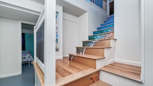 Un escalier avec des marches en bois et des éléments décoratifs bleus, menant à l’étage supérieur.