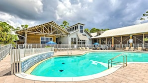 Une piscine avec une terrasse en bois, des chaises longues et des parasols.