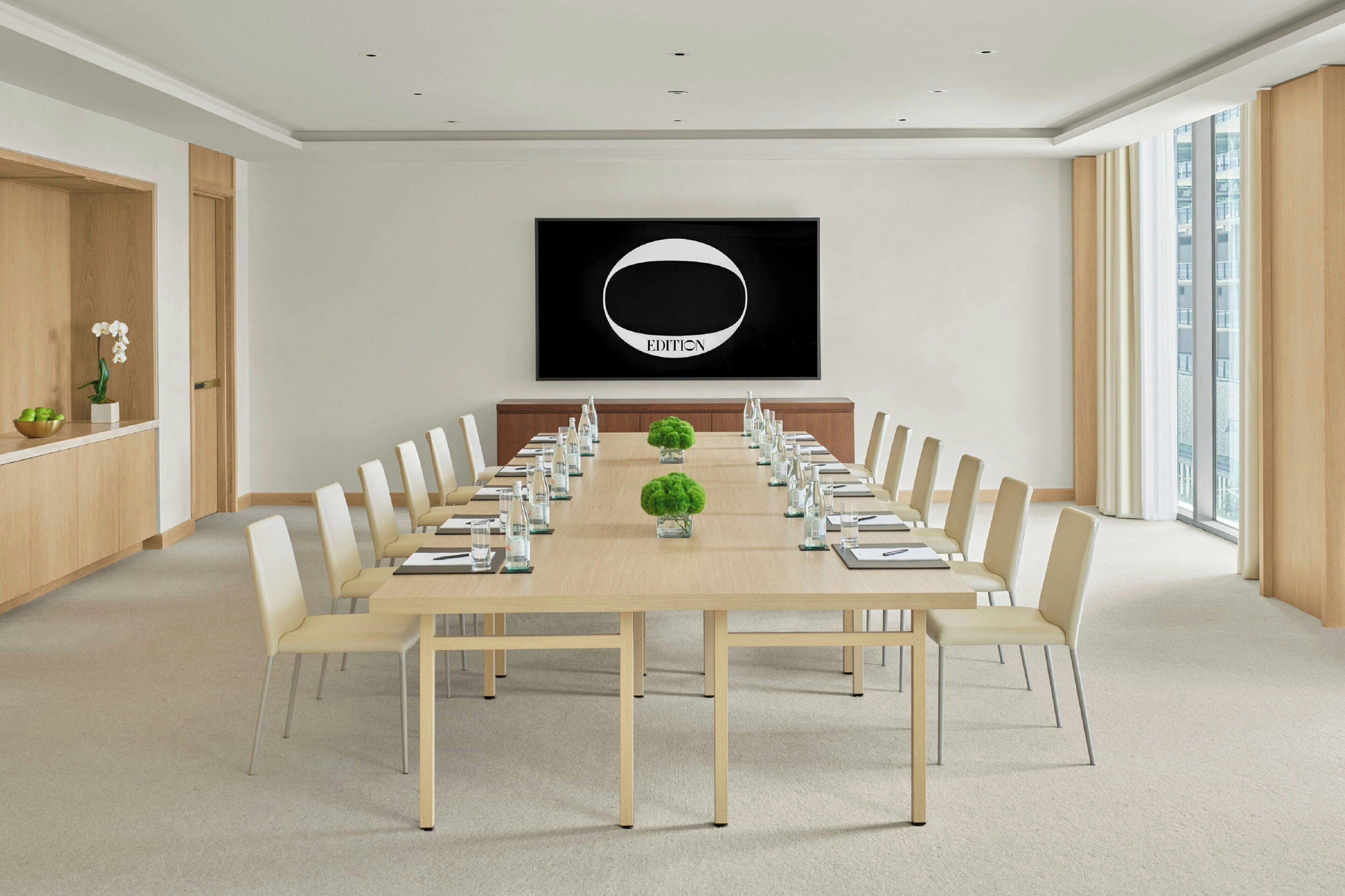 A conference room with a long table, chairs, and a large framed picture on the wall.