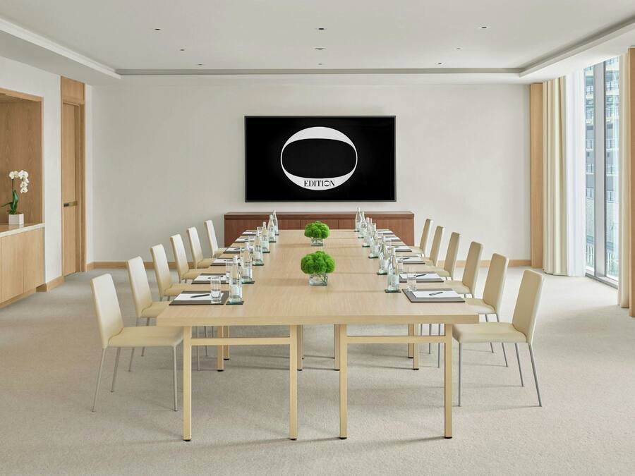 A conference room with a long table, chairs, and a large framed picture on the wall.