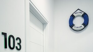 Un couloir avec une porte blanche, une armoire noire et une bouée de sauvetage accrochée au mur.