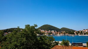 Une ville côtière avec des bâtiments, une colline et un ciel bleu dégagé.