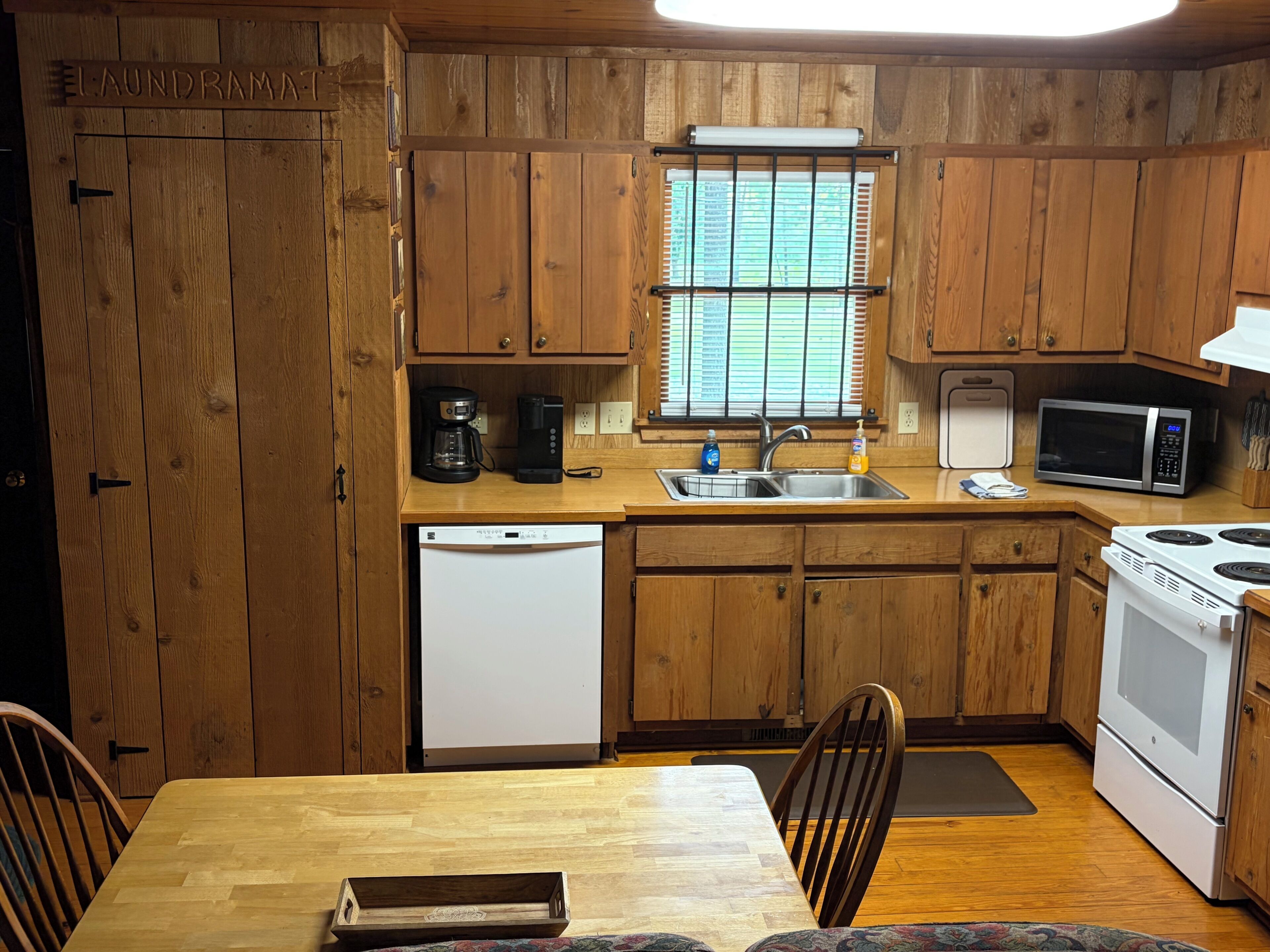 A wooden kitchen with a refrigerator, microwave, coffee maker, and sink.