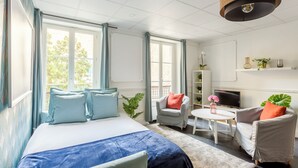 Een moderne hotelkamer met een groot bed, twee fauteuils, een kleine tafel en een televisie.