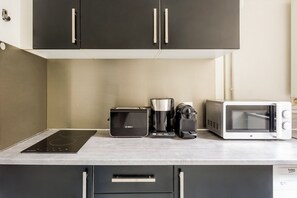 Una kitchenette equipada con una placa de inducción Bosch, cafetera, tostadora y microondas.