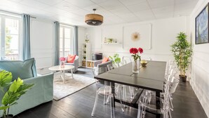 Een moderne eetruimte met een donker houten tafel, transparante plastic stoelen en een lichtblauwe bank.