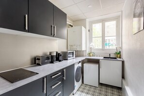 Una cocina compacta equipada con lavadora integrada, microondas y cafetera.