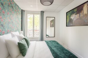 Un dormitorio con cama, ventanal con vistas, un cuadro y un espejo.