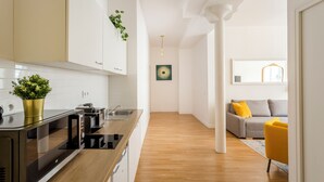 A modern kitchen with a built-in microwave and stove, wooden flooring, and a plant on the counter. - Merveil - Family Suite - Louvre - Sentier II (Paris)